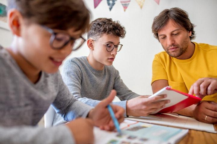 A parent helps his virtual school students with their homework on their own schedule